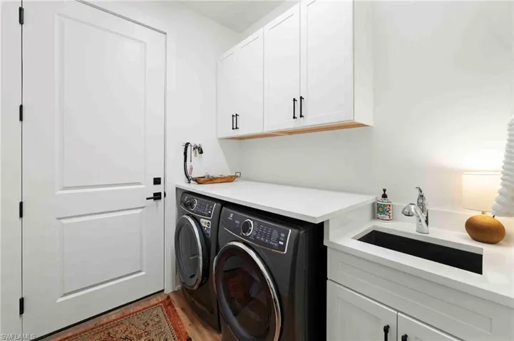 White shaker cabinetry with black hardware, white countertop, and integrated black sink