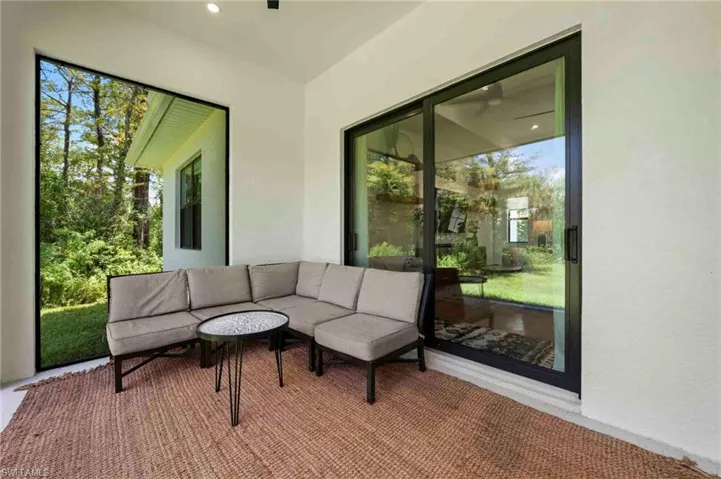 Covered outdoor patio with a large picture window, recessed lighting, and a wide sliding glass door