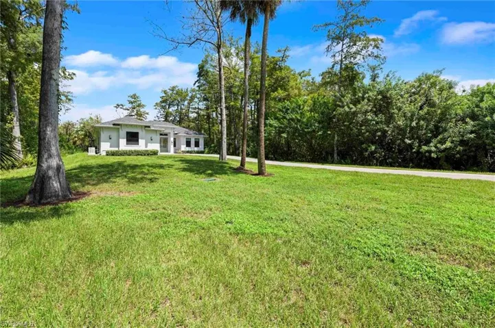 White exterior residence with a gray shingle roof, dark-framed windows, and a paved driveway