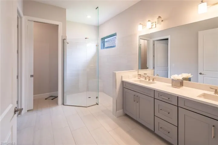 Bathroom featuring walk in shower, dual bowl vanity, and tile flooring