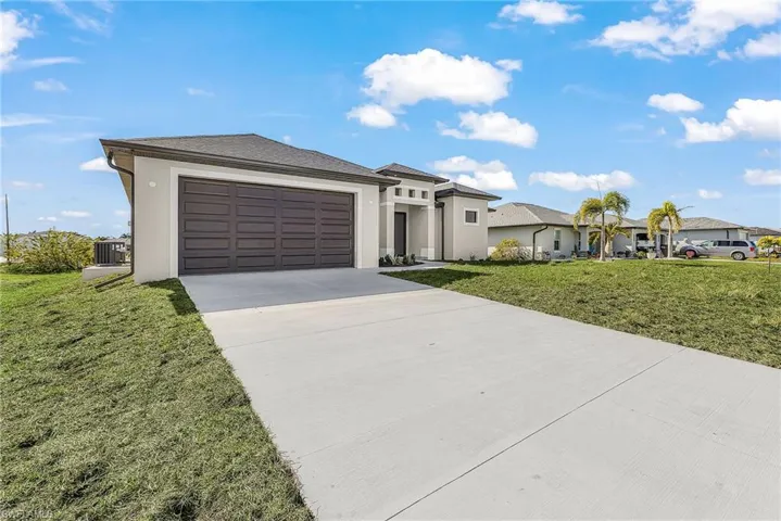 Prairie-style house with a front lawn, driveway, stucco siding, and a garage