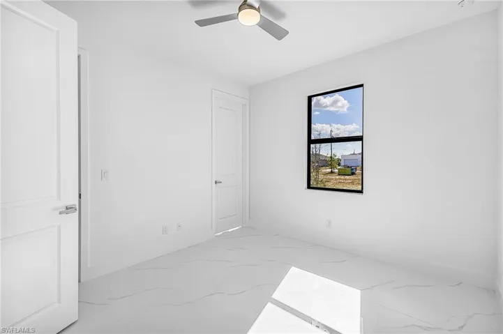 Unfurnished bedroom featuring light marble finish floors and ceiling fan