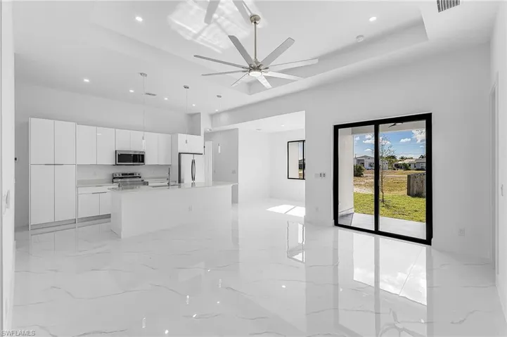 Kitchen with open floor plan, white cabinetry, modern cabinets, a kitchen island with sink, and pendant lighting