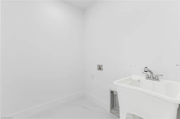 Washroom featuring washer hookup and light marble finish flooring