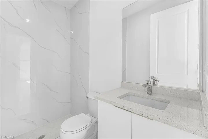 Full bath featuring vanity and a marble finish shower