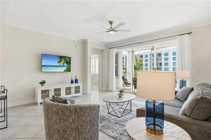 Spacious living area featuring neutral wall tones, tile flooring, and crown molding