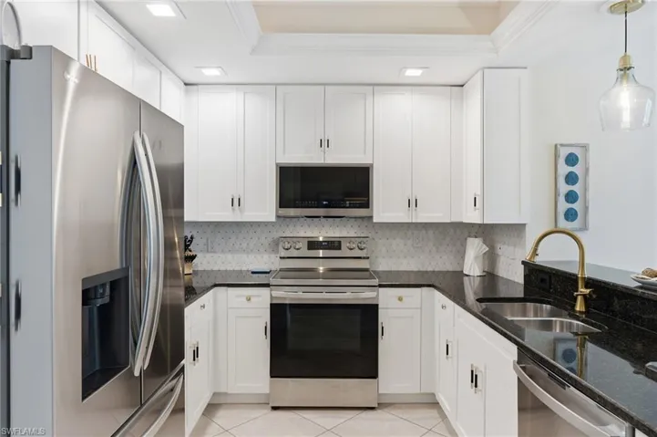 U-shaped kitchen with white cabinetry, dark stone countertops, stainless steel appliances, a tile backsplash, and recessed lighting