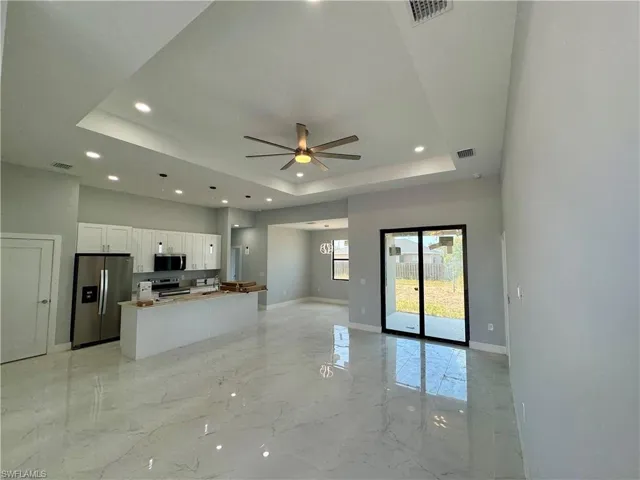 Kitchen featuring a raised ceiling, white cabinets, open floor plan, stainless steel appliances, and recessed lighting
