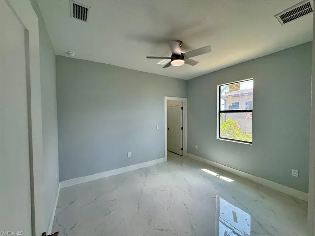 Unfurnished room with marble look tiles and ceiling fan