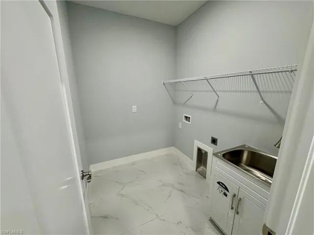 Washroom with hookup for an electric dryer, washer hookup, light marble finish floors, and cabinet space