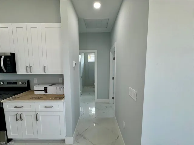 Hallway featuring baseboards and light marble finish flooring