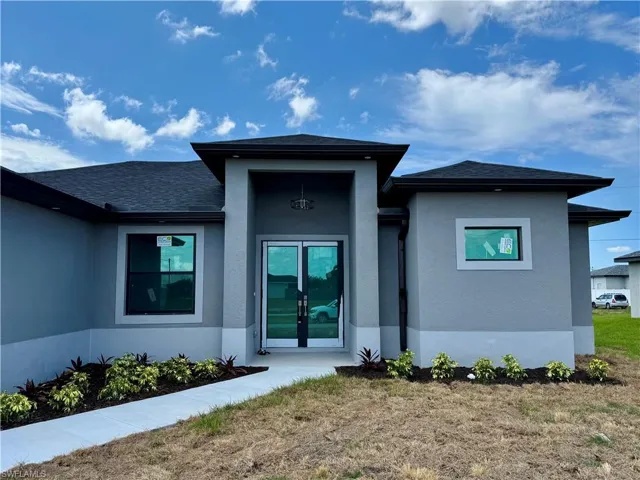 Property entrance featuring stucco siding, roof with shingles, french doors, and a yard