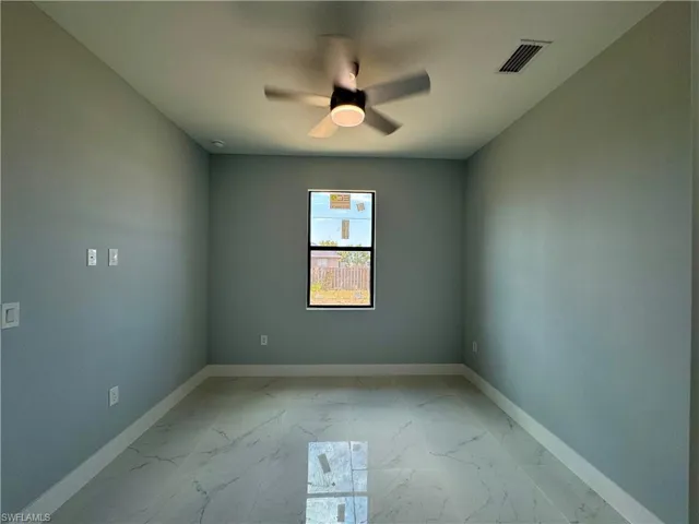Unfurnished room featuring light marble finish flooring and a ceiling fan
