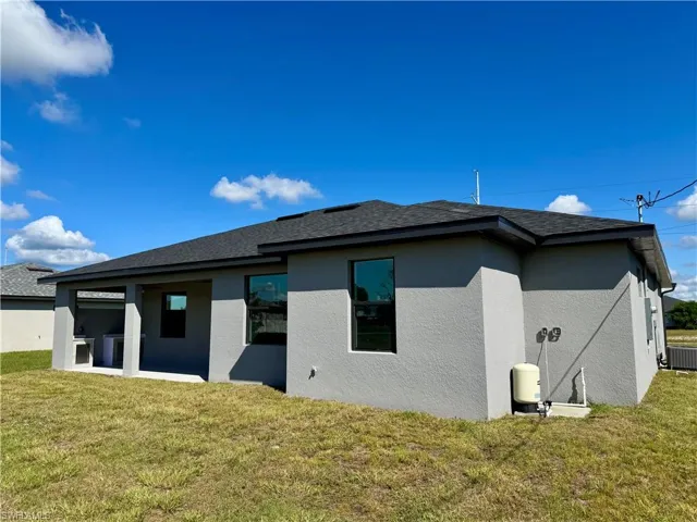 Back of house with stucco siding, a patio, and a lawn