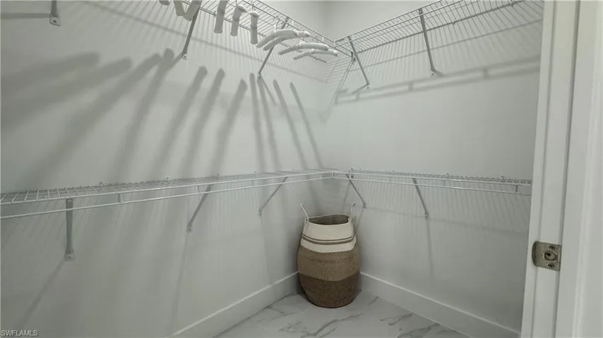 Spacious closet featuring light marble finish flooring