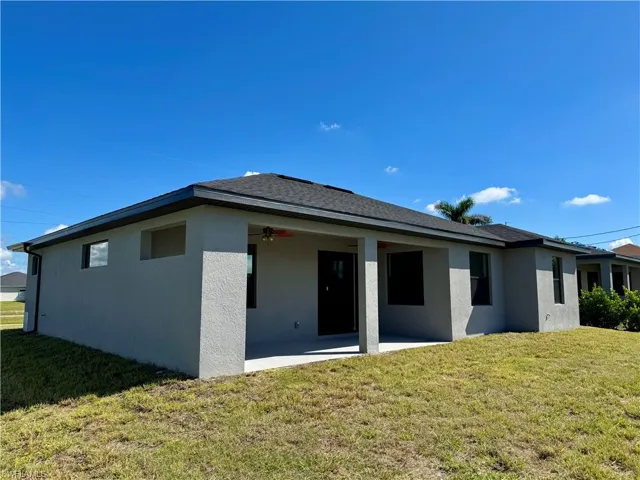 Back of house with a lawn, a patio area, ceiling fan, and stucco siding