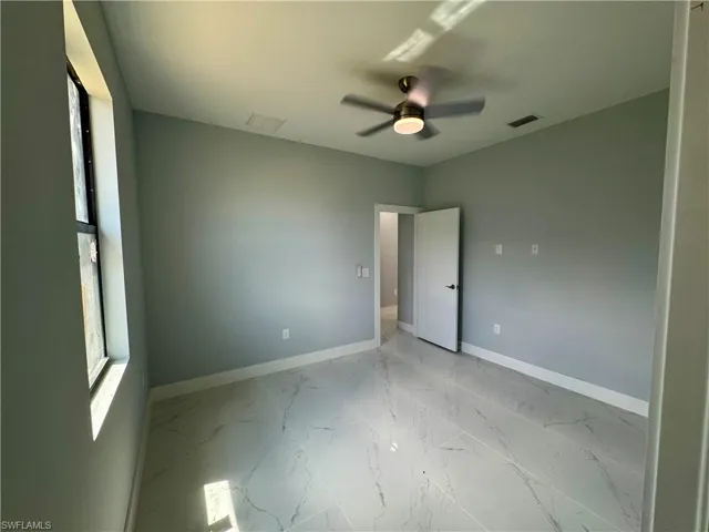 Unfurnished bedroom with light marble finish flooring and a ceiling fan