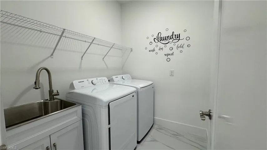 Laundry room with light marble finish floors and washing machine and clothes dryer