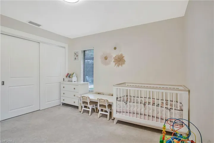 Carpeted bedroom featuring a closet and a crib