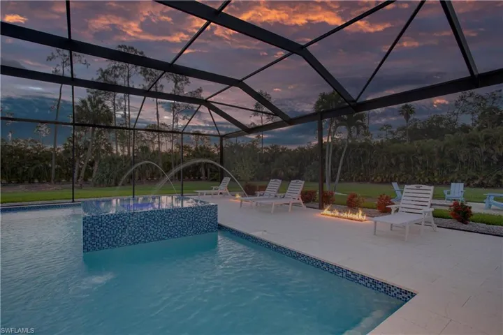 Pool at dusk with a patio, a lanai, and a pool with connected hot tub