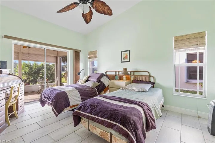 Bedroom with ceiling fan, vaulted ceiling, and light tile patterned floors