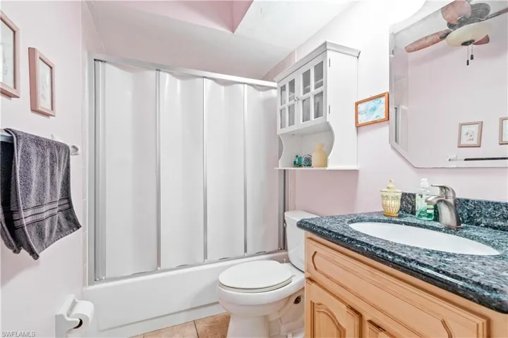 Full bathroom with vanity, toilet, shower / bath combination with glass door, and tile patterned flooring