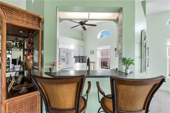 Kitchen featuring kitchen breakfast bar, ceiling fan, white cabinetry, light tile patterned flooring, and white refrigerator with ice dispenser
