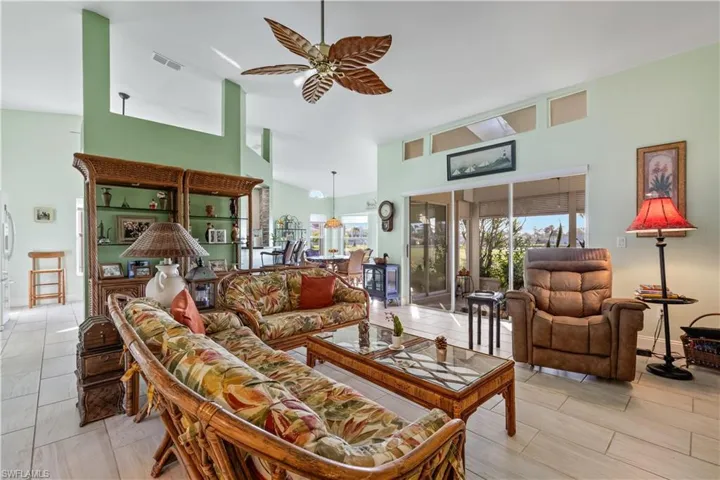 Living room featuring ceiling fan and high vaulted ceiling