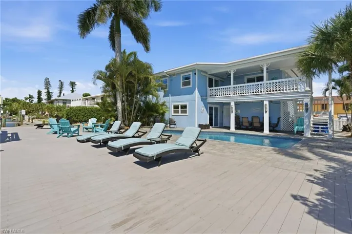 Expansive outdoor living area featuring a ground-level pool, an upper-level balcony with white railing, and a spacious deck - Virtually Edited Image