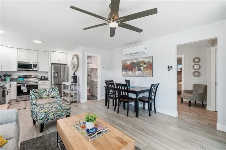 Open-concept living area featuring wood-finish flooring, a contemporary ceiling fan, and recessed lighting - Virtually Edited Image