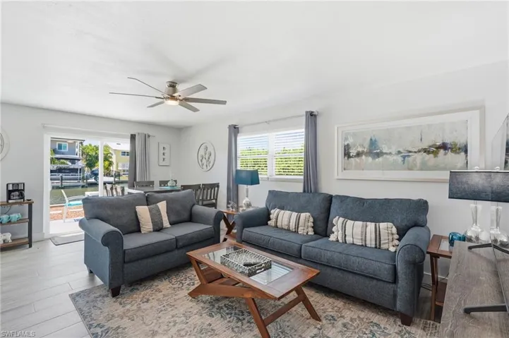 Open-concept living area featuring light wood-finish flooring and a ceiling fan - Virtually Edited Image