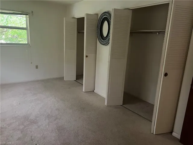 Unfurnished bedroom featuring light carpet and two closets