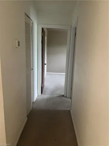 Hallway featuring carpet and baseboards