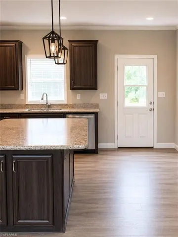Open-concept kitchen featuring an island with a stone countertop, dark wood-finish cabinetry, stainless steel dishwasher, and wood-finish flooring