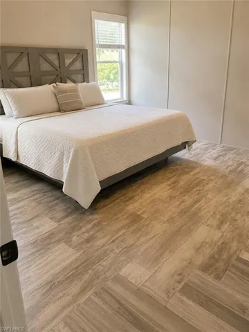 Wood-look plank tile flooring throughout this room, featuring a window with white blinds and white trim
