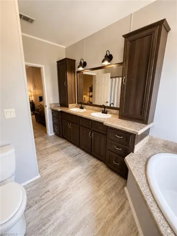 Bathroom featuring a double vanity with dark wood-finish cabinetry, light-colored countertops, and dual vessel sinks