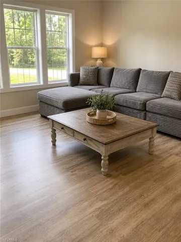 Spacious room featuring wood-finish flooring, light-toned wall paint, and multiple windows with white trim