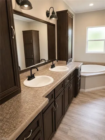 Dual vanity with dark wood-finish cabinetry, integrated sinks, and bronze-finish faucets