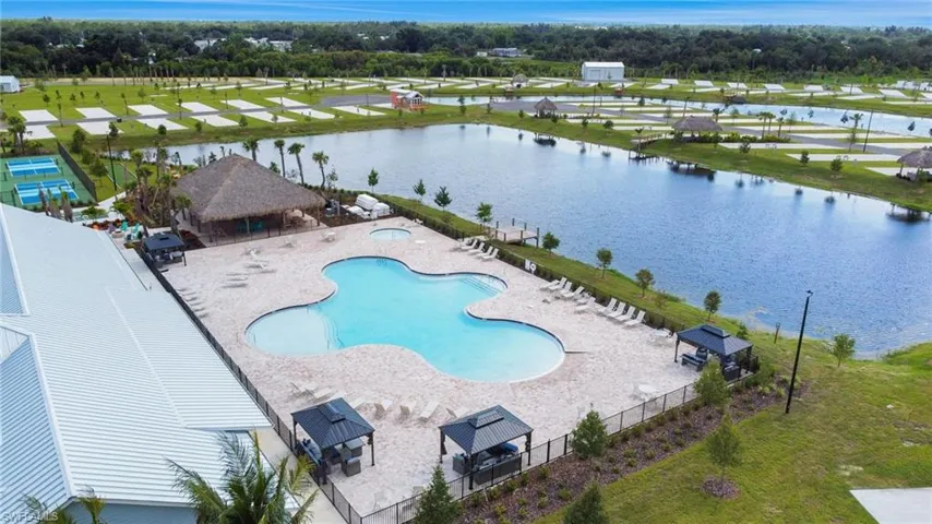 Community pool with a patio, view of scattered trees, and a water view