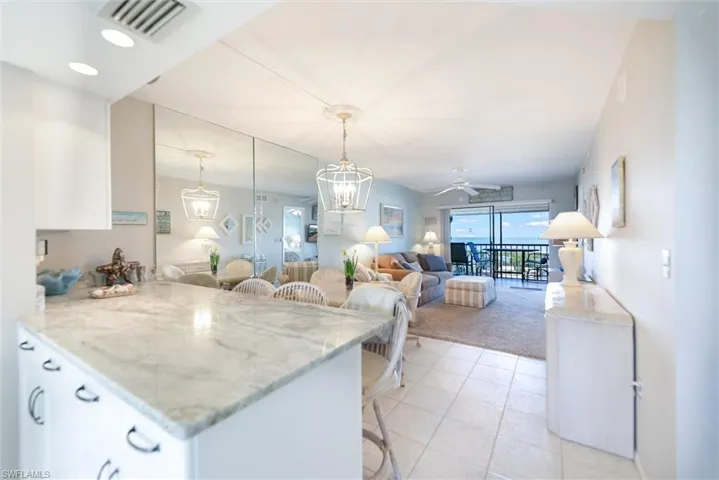 Kitchen with a breakfast bar, ceiling fan, light stone countertops, and white cabinets