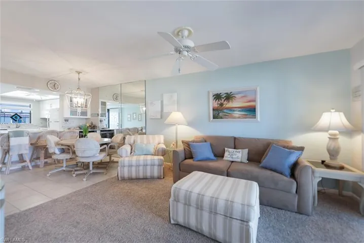 Carpeted living area featuring suspended lighting, a ceiling fan, plenty of natural light, and tile patterned floors