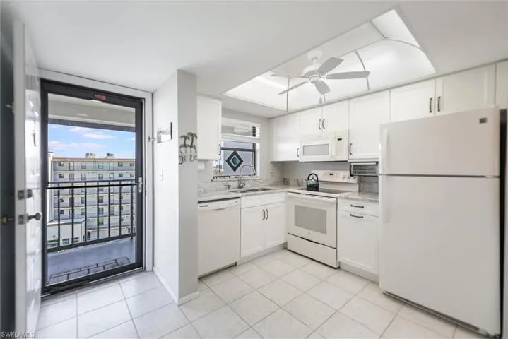 Kitchen featuring white appliances, white cabinetry, a ceiling fan, and light tile patterned flooring