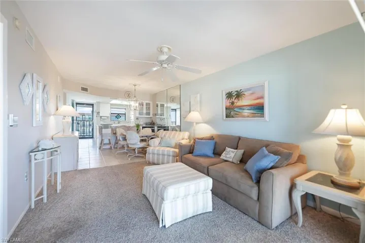 Tiled living room featuring a ceiling fan and carpet flooring
