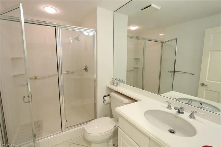Bathroom with tile patterned flooring, visible vents, toilet, vanity, and a stall shower