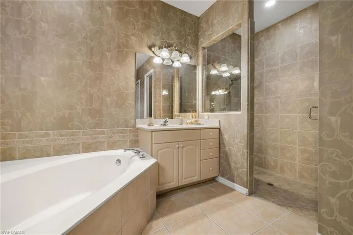 Full bathroom featuring vanity, a garden tub, tile patterned flooring, and wallpapered walls