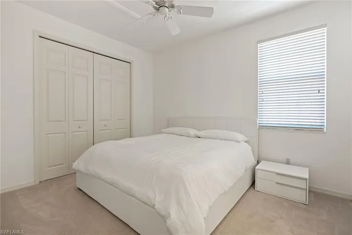 Bedroom with light carpet, a closet, baseboards, and a ceiling fan