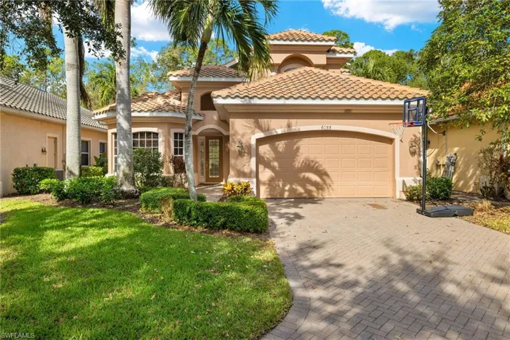 Mediterranean / spanish home with stucco siding, decorative driveway, an attached garage, a front lawn, and a tile roof
