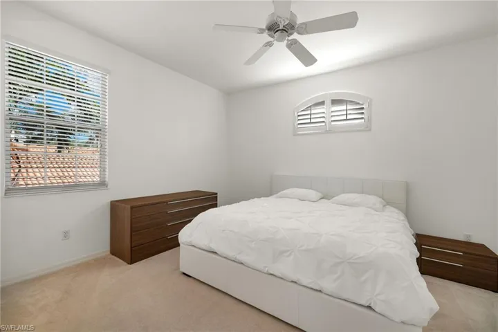 Bedroom featuring ceiling fan, multiple windows, and light colored carpet