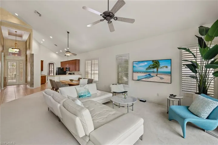 Living room featuring high vaulted ceiling, ceiling fan, visible vents, and light tile patterned floors