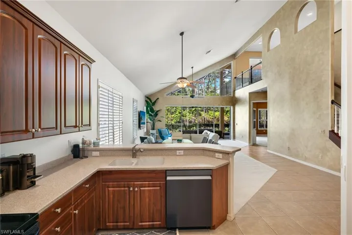 Kitchen featuring open floor plan, a peninsula, ceiling fan, dishwasher, and a sink